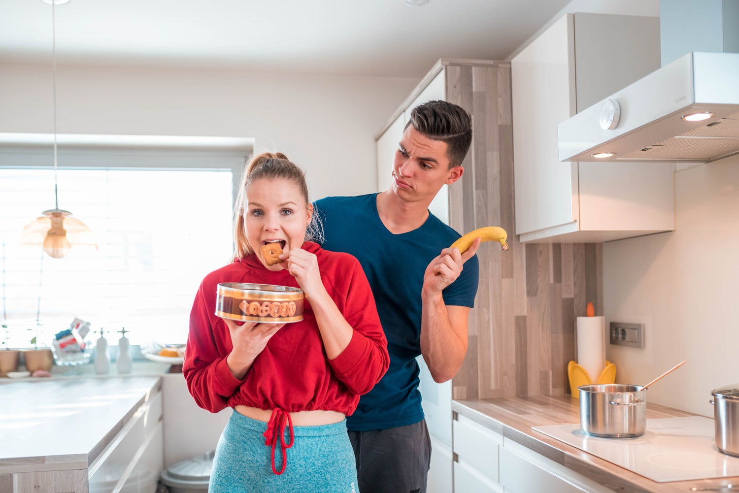 2 people, she is eating cookies and he is holding a banana